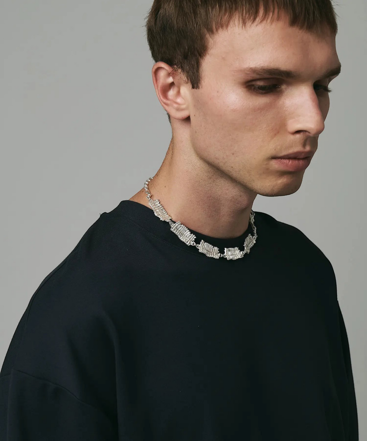 ROLE STOREのHERGO×ISAJI YUGOコラボによる、キャタピラーモチーフのインダストリアルなシルバー925ネックレスを着用した男性