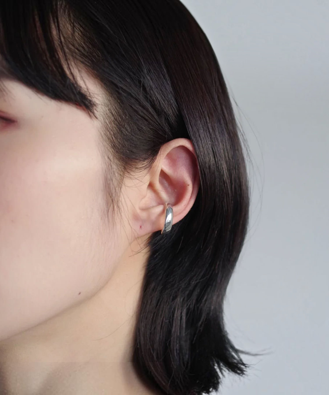 ROLE STOREのStreamlineイヤーカフ。シルバー925素材の流線形フォルムが特徴的な、シンプルで洗練された片耳用イヤーカフを着用した様子。